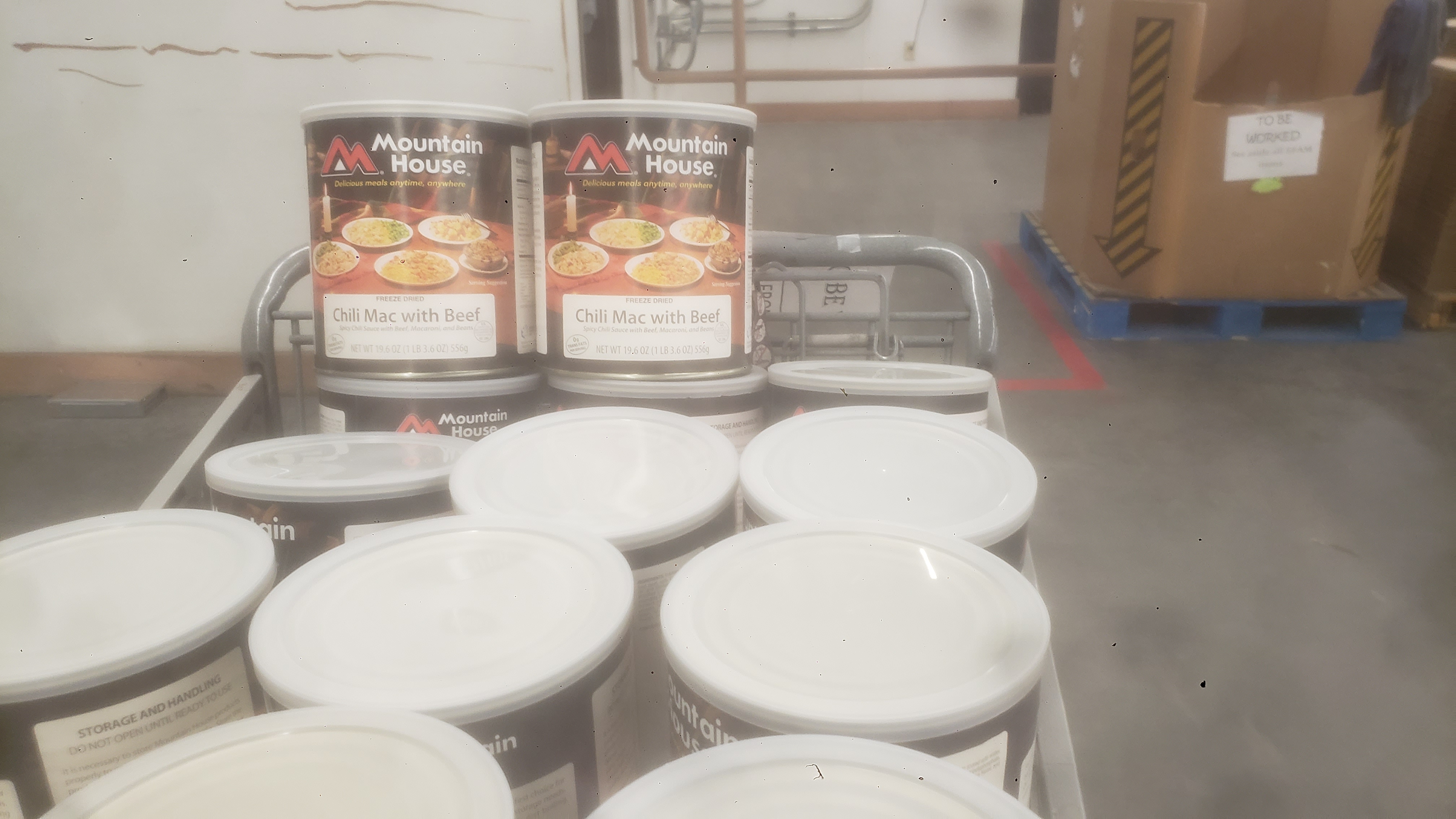 Shopping cart full of big cans of chili mac with beef.